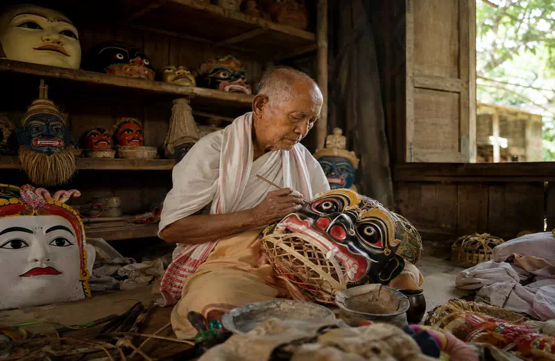 A monk crafting a traditional bamboo and clay mask at a Satra monastery in Majuli, Assam