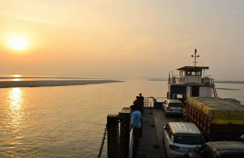 A passenger ferry crossing the wide Brahmaputra River at sunrise on the way to Majuli island, Assam