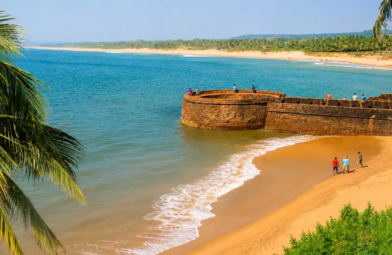 Fort Aguada overlooking Candolim Beach with golden sand and turquoise sea.