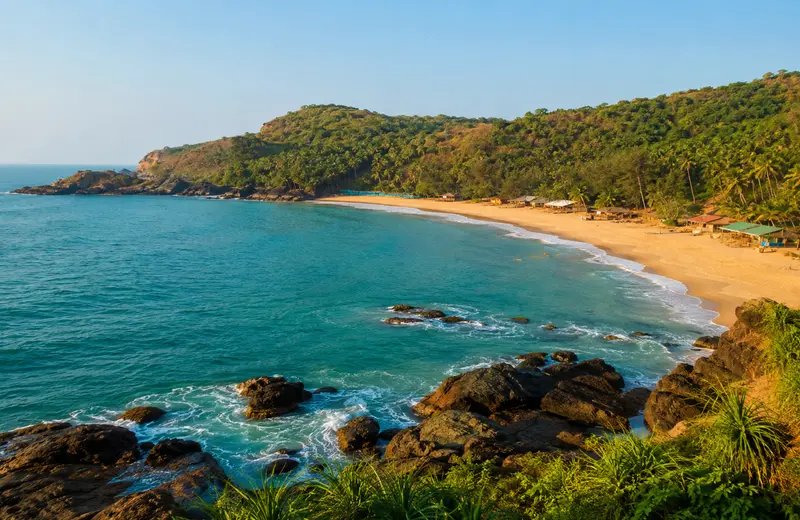 Kudle Beach in Gokarna with rocky cliffs, palm-lined shore and calm turquoise Arabian Sea water