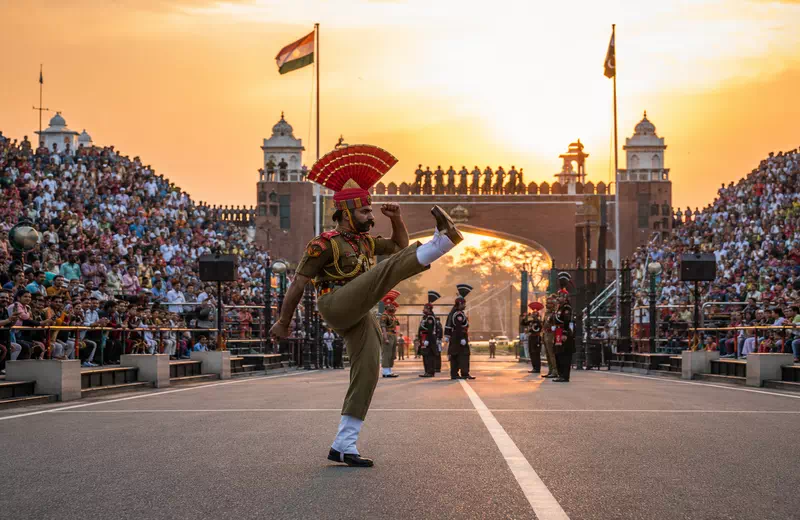 Soldiers performing the high-kick march during the Wagah Border Beating Retreat ceremony at sunset