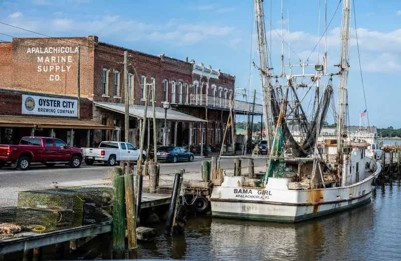 Historic brick storefronts and a working seafood dock in downtown Apalachicola, Florida, on the Forg