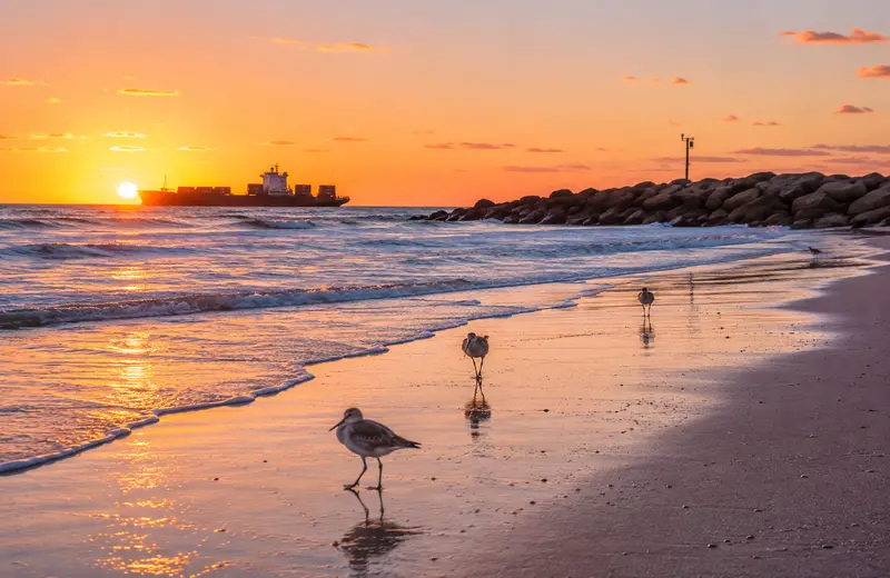 Sunrise over the beach and jetties in Port Aransas, Texas.