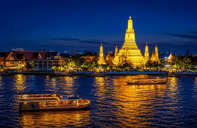 Wat Arun view point at night from across the Chao Phraya River, the illuminated Temple of Dawn reflected in the water in Bangkok.