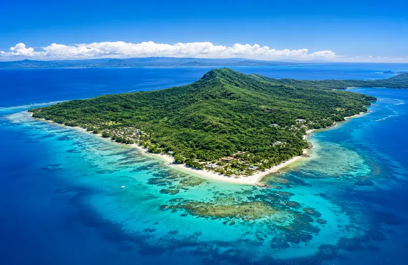 Beqa Island, Fiji, with tropical rainforest, coral reefs, and turquoise ocean waters.